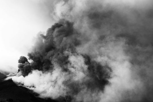 Black and white image of a volcanic eruption with thick smoke clouds.