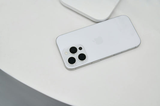 A sleek white smartphone with a triple camera setup placed on a white surface, showcasing modern design.