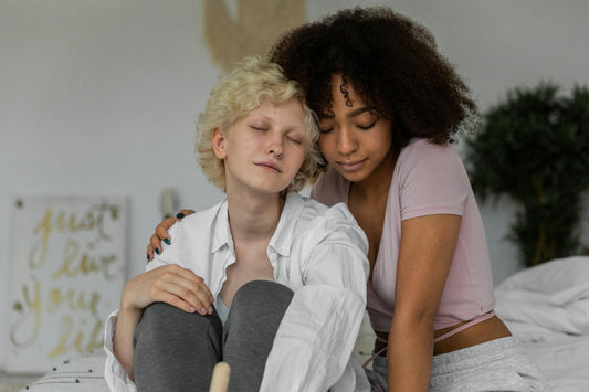 Romantic young multiracial lesbian couple in comfy clothes cuddling with closed eyes while relaxing together at home