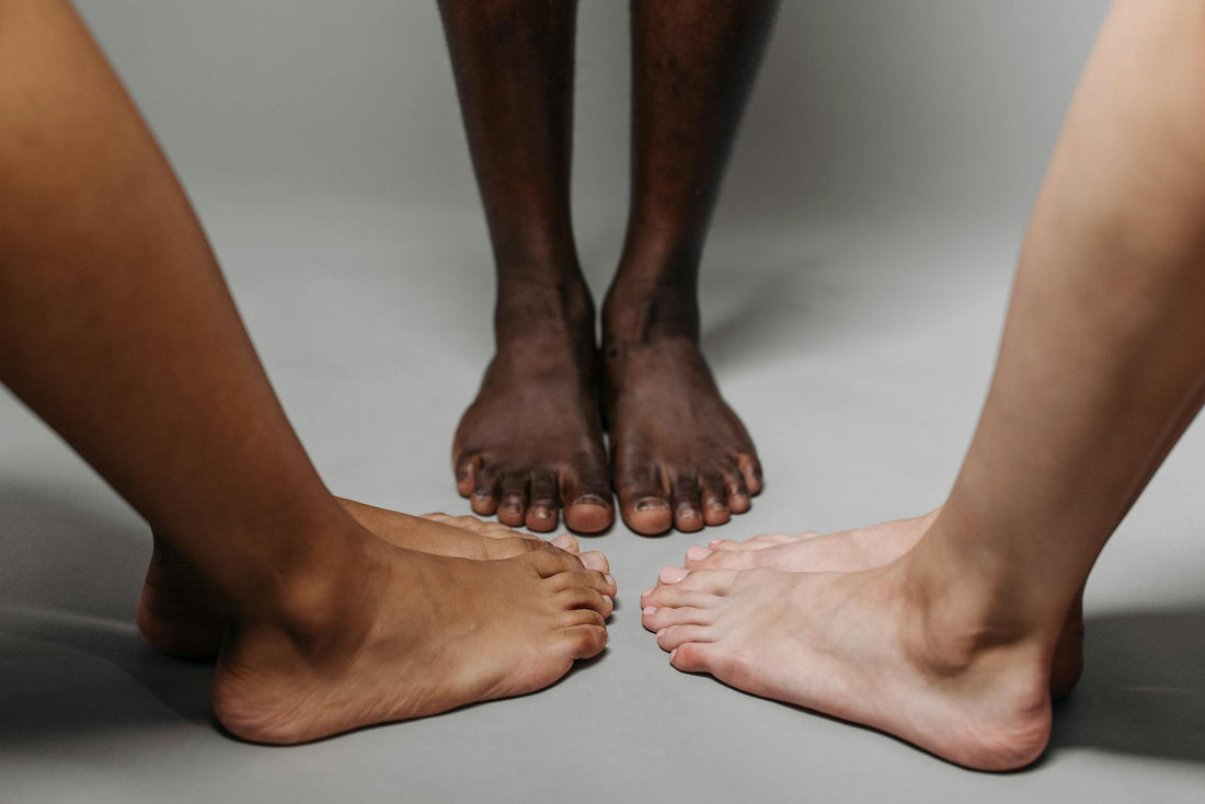 Close-up of diverse adult feet on a neutral background symbolizing unity.