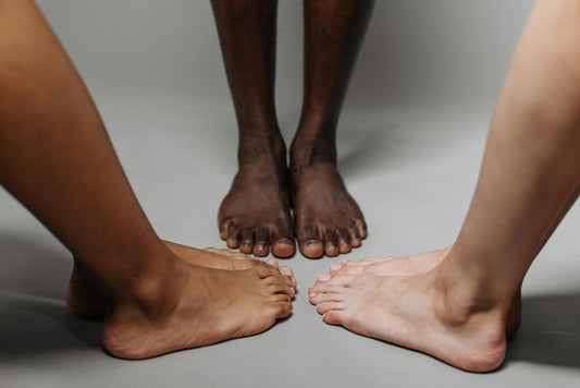 Close-up of diverse adult feet on a neutral background symbolizing unity.