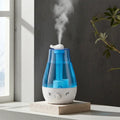 Blue QuietAura humidifier with soft amber LED glow on a wooden nightstand