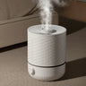 White humidifier with text highlighting features on a carpeted floor.
