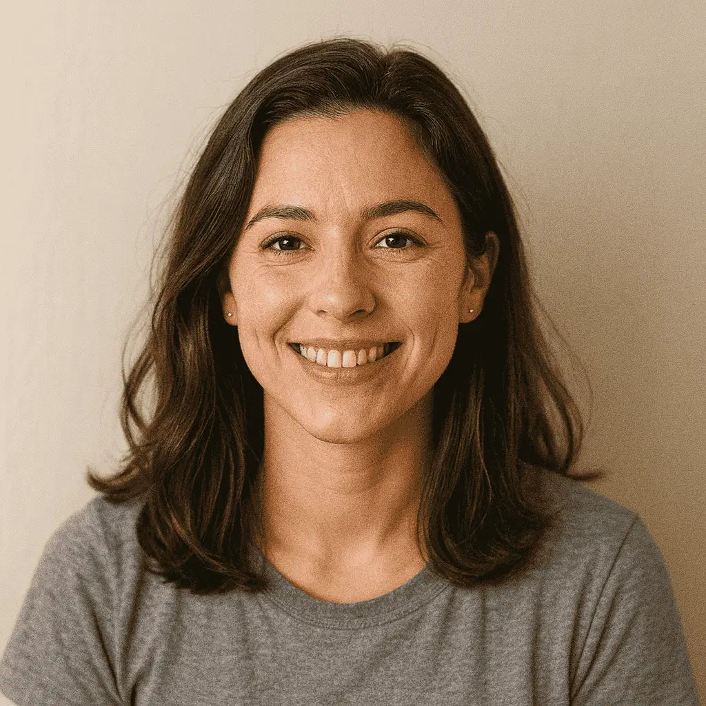 Woman with shoulder-length brown hair wearing a gray shirt against a beige background