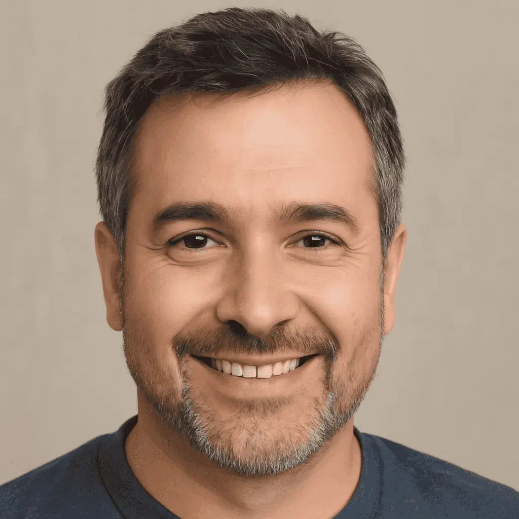 Man with a beard and mustache smiling against a beige background